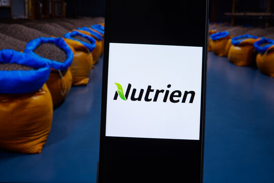 Nutrien company logo displayed against a background of fertilizer bags. Nutrien is an American producer and marketer of crop nutrients and fertilizers.