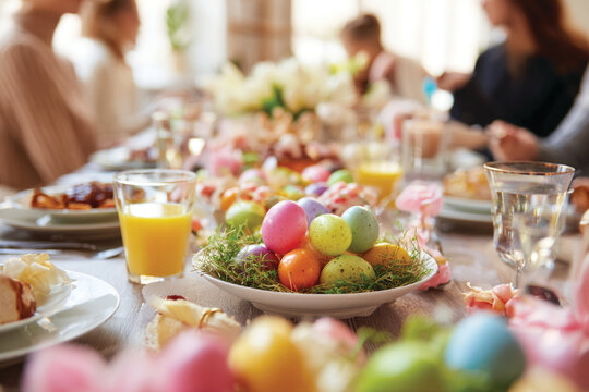 Happy family having Easter dinner together, table setting with traditional food, colorful eggs and spring flowers for Easter celebration	
