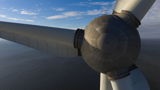 Aerial view of the stark white wind turbine blades slicing through the sky above the tranquil, dark blue waters of the sea, Espel, Flevoland, Netherlands.