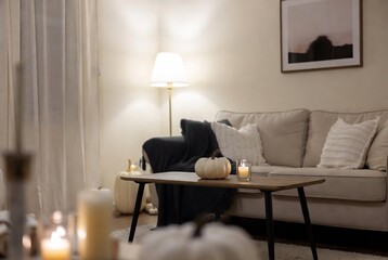 Naklejka premium A cozy living room scene with candles, pumpkins, and a muted color palette.