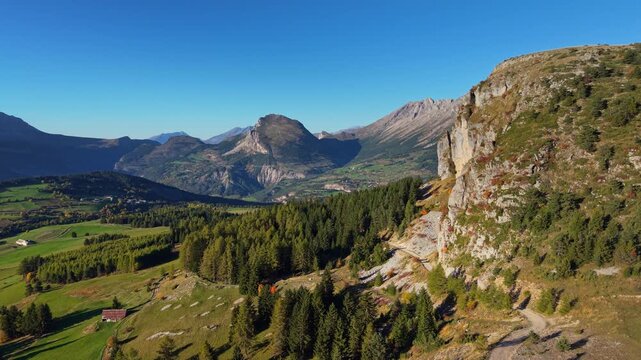 Aerial view of Devoluy Massif mountain valley with forested slopes and rocky cliffs in Hautes-Alpes, French Alps