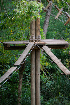 Tree top adventure course with wooden planks and ropes in a forest setting for climbing and exploring near the ground