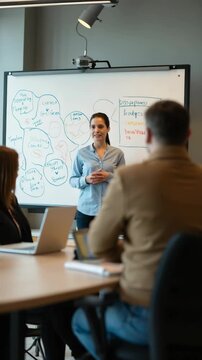 Female Business Coach for Company Management Explains How to Train your Team Efficiently in a Workshop Inside Creative Office. Woman Trainer Writing on Whiteboard and Training Interactive Em.