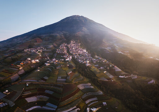 Aerial view of a village nestled on the slopes of a majestic mountain, terraced fields cascading down in vibrant hues, Nepal van Java, Jawa Tengah, Indonesia.