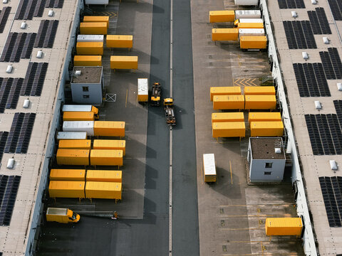 Aerial view of yellow containers contrasting against the dark solar panels and gray concrete, a stark industrial landscape, North Rhine-Westphalia, Germany.