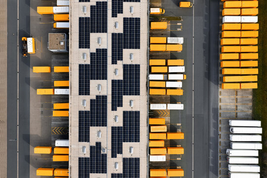 Aerial view of rows of brightly colored containers contrasting against the dark solar panels on the roof, North Rhine-Westphalia, Germany.
