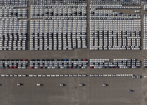 Aerial view of a multitude of cars arranged in neat rows, creating a geometric pattern of whites, reds, and blues against a neutral ground, Shanghai, Shanghai, China.