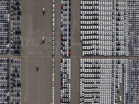 Aerial view of serried ranks of cars in a vast parking lot, patterns of monochrome vehicles punctuated by red and blue accents, Shanghai, Shanghai, China.