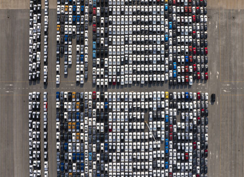 Aerial view of a vast, orderly grid of vehicles in neat rows, reflecting sunlight on their roofs, presenting a mesmerizing pattern from above, Shanghai, Shanghai, China.