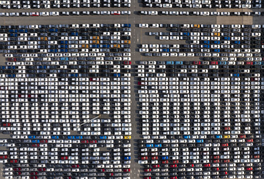 Aerial view of tightly packed rows of vehicles displaying a monochromatic sea of white and subtly interspersed with splashes of blues, blacks, and yellows, Shanghai, Shanghai, China.