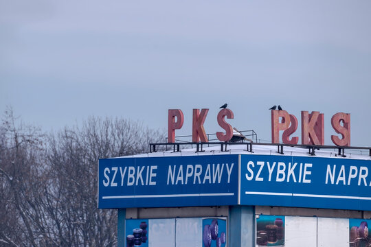 Polska, Ostrowiec Świętokrzyski, 16 lutego 2026, 12:28. PKS (Polska Komunikacja Samochodowa) i napis &bdquo;Szybkie Naprawy&rdquo;. Budynek zwieńczony jest dużymi czerwonymi literami, a  na wierzchu ptaki - kawki