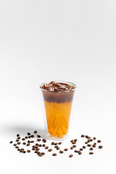 Refreshing bumble orange citrus juice and black coffee espresso drink with ice in a transparent double wall glass on white background 