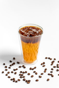 Refreshing bumble orange citrus juice and black coffee espresso drink with ice in a transparent double wall glass on white background 