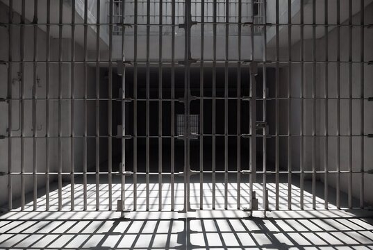 A prison cell with a barred window and light casting shadows.
