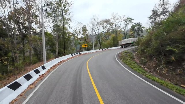 A mountain road in northern Thailand, with large trucks slowly ascending.