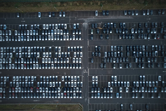 Aerial view of rows of cars parked in neat formation, the asphalt reflecting a somber light, creating a stark contrast with the vehicles, Stone, England, United Kingdom.
