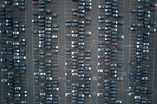 Aerial view of cars neatly aligned in a parking lot, each a metallic glint against the dark asphalt, creating a rhythmic urban pattern, Stone, England, United Kingdom.