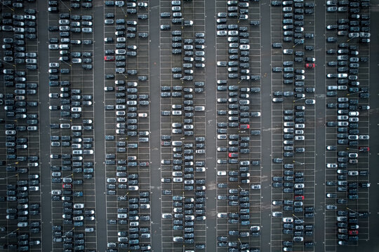 Aerial view of neatly arranged cars in a vast parking lot create a mesmerizing geometric pattern, showcasing urban order and vehicular density, Stone, England, United Kingdom.