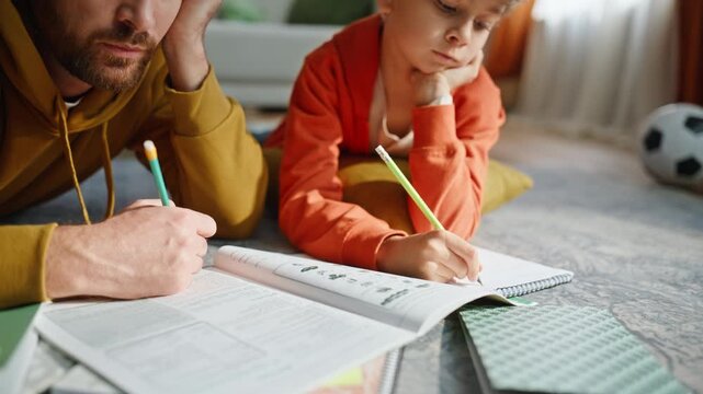 Father schoolboy hands writing notebook making homework together closeup. 