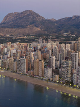 Aerial view of golden light shimmering on skyscrapers along the coastline, as mountains rise in the distance, Benidorm, Valencian Community, Spain.