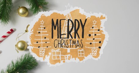 Showing torn orange cutout MERRY CHRISTMAS on gray tabletop, with pine sprigs, gold baubles © vectorfusionart