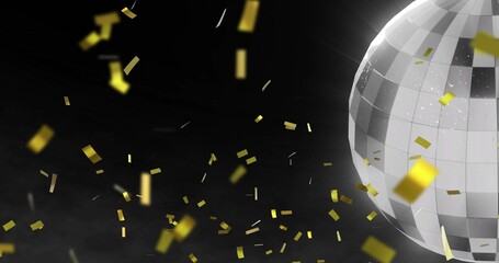 Rotating silver mirrored disco ball reflecting light in dark studio, with gold confetti, copy space