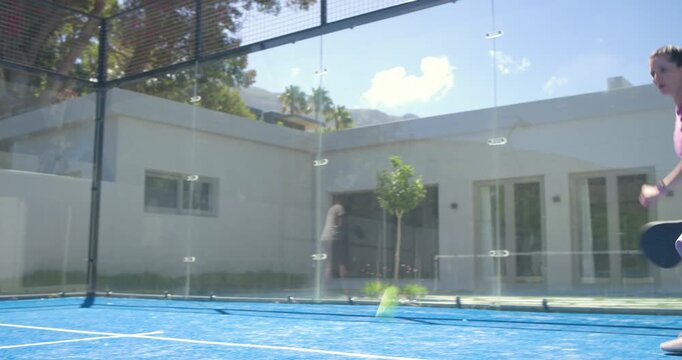 Sports player in purple tracking lobbed ball with paddle, lunging and volleying for point on court