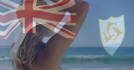 Naklejka premium Adjusting sun hat, woman wearing swimsuit facing sea at beach, UnionJack overlay and dolphin emblem