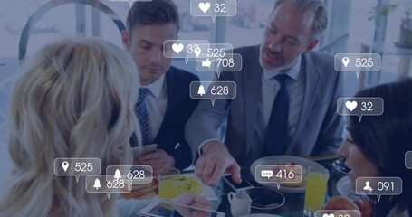 Discussing colleagues in suits at cafe breakfast table, pointing at tablet and phone notifications © vectorfusionart