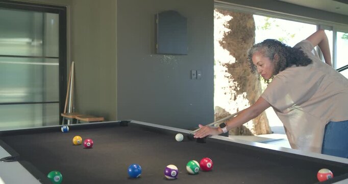 African American woman entering rec room, practicing shots on pool table with cue ball, copy space
