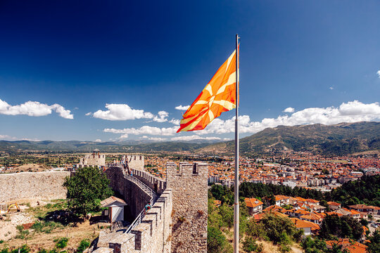 View of the vibrant Macedonian flag fluttering atop the ancient fortress walls, overlooking the city against a backdrop of mountains, Ohrid, Municipality of Ohrid, North Macedonia.