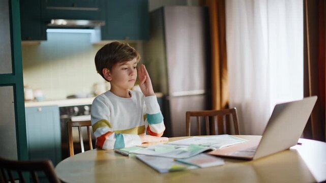 Online pupil raising hand answering teacher question remotely in kitchen closeup