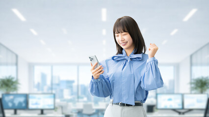 スマートフォンを見てガッツポーズをする若い女性ビジネスパーソン, Young businesswoman making a fist pump while looking at a smartphone © Trickster*