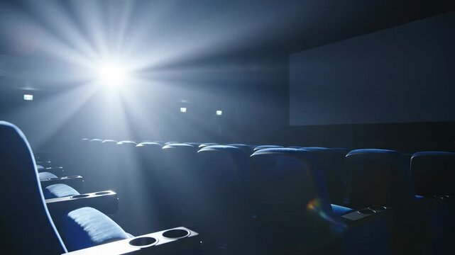 Video of blank cinema screen casting moving light in a dark hall, modern multiplex interior background for film promotion and creative advertising.
