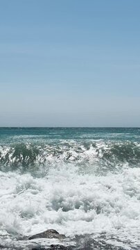 Resting on the beach with stormy turquoise waves of the sea in Almunecar, Spain, under dramatic skies and strong surf.