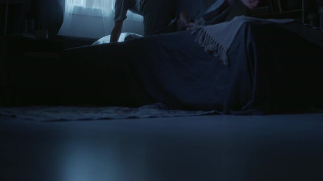 Ground level shot of young adult woman walking toward bed in bedroom during late night falling onto pillow while suffering from insomnia, copy space
