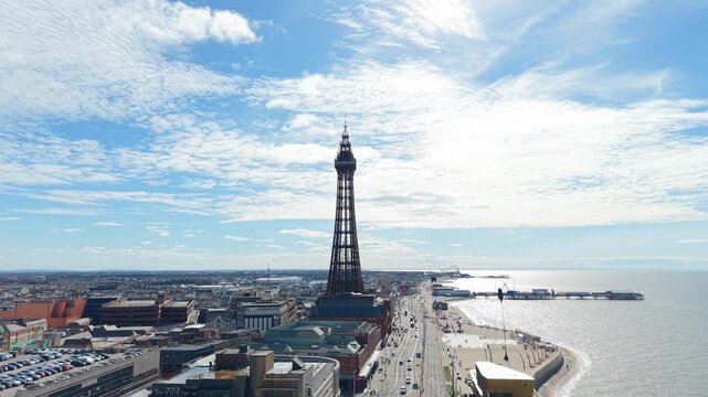 Aerial Drone footage of Blackpool sea front and tower, the drone gradually pulling away over the sea to reveal the north Pier