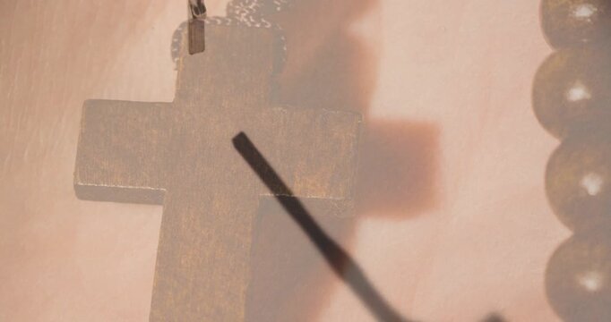 Swinging metal crucifix pendant falling closeup on cloth with big cross, chain, beads, copy space