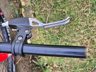 Obraz premium Close up view of bicycle handlebar with metal brake lever and black grip outdoors on grass