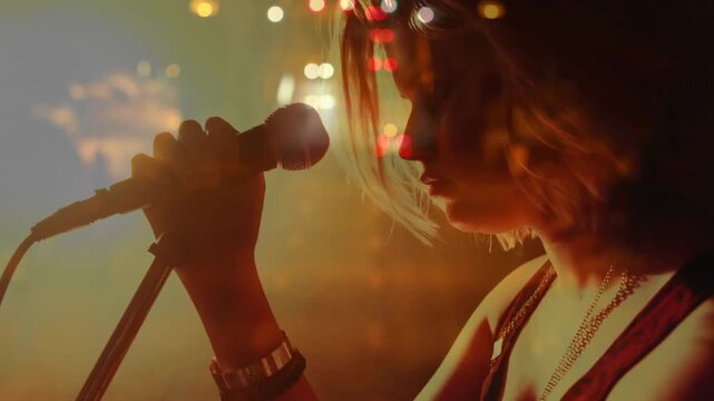 Camera pulling back showing woman singer holding mic inhaling singing song as street bokeh blending