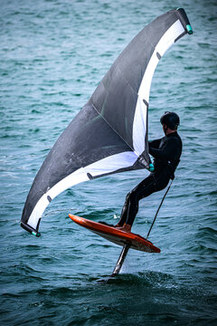 Foil surfing on the water with a wing sail at a coastal location during daylight