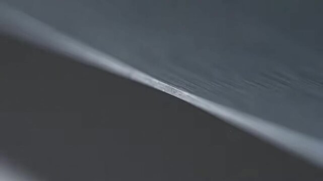 Extreme close up of sharp knife edge moving slowly in focus, demonstrating precision and sharpness