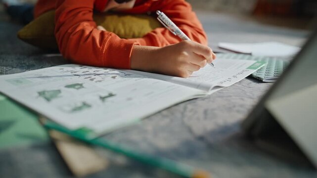Serious pupil making notes notebook doing homework learning lesson closeup.