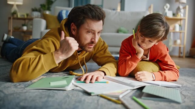 Father boy studying home living room floor closeup. Dad explaining school task 