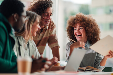Diverse students collaborating, laughing during an office meeting