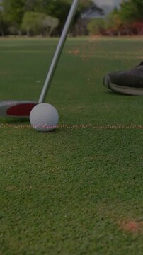 Vertical video: Golfer swinging putter causing overlay guiding golf ball into cup, aiming for hole