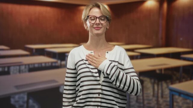 Woman hand on chest and right hand raised palm out as pledge inside building; sincerity commitment respect.