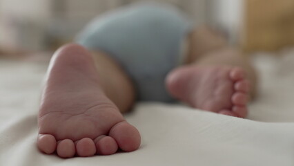 Baby lying on bed, feet in focus, soft texture, toes curled, resting pose, childhood innocence, home setting, relaxed, organic moment, natural light