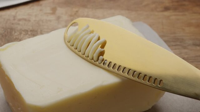 Butter is scraped off with a special butter knife from a pack of butter into a recognizable shape