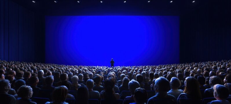 The stage with a lone speaker in front of a giant blue screen
